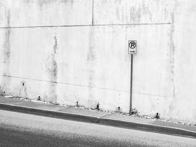 A no parking sign in front of a concrete wall